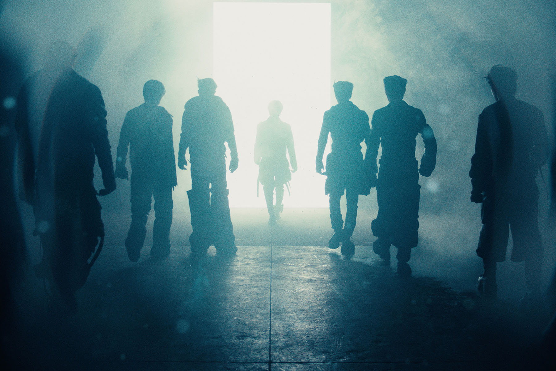 Seven silhouetted figures walking toward a bright, misty light
